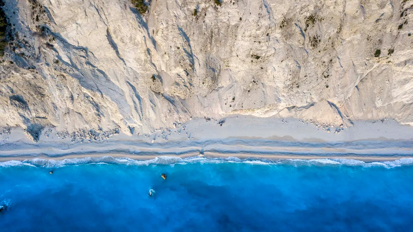 Aerial view of pale cliffs meeting deep blue water at Egremni beach.