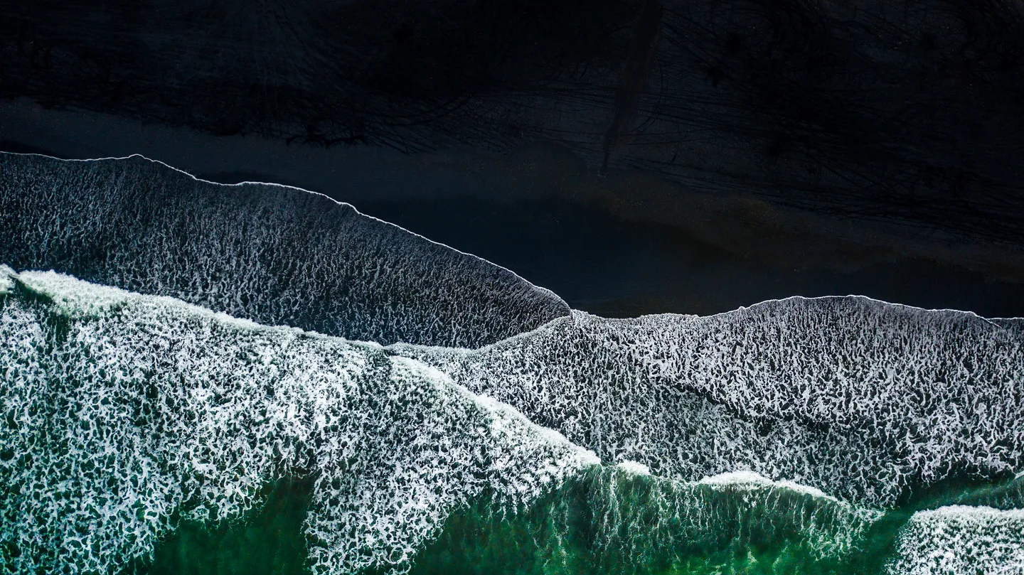 A volcanic beach on the coast of New Zealand seen from above.
